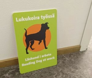 Lukukoira työssä -kyltti.