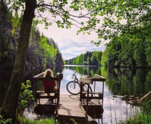 Kuvassa nainen, pyörä ja järvi.