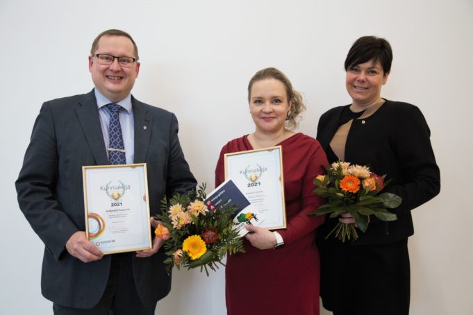 Kaupunginjohtaja Oskari Auvinen, opetuspäällikkö merja Lehtonen ja sosiaali- ja terveysjohtaja Marika Lanne seisovat rinnakkain ja esittelevät kunniakirjoja. Näkyvillä myös onnittelukukkia.