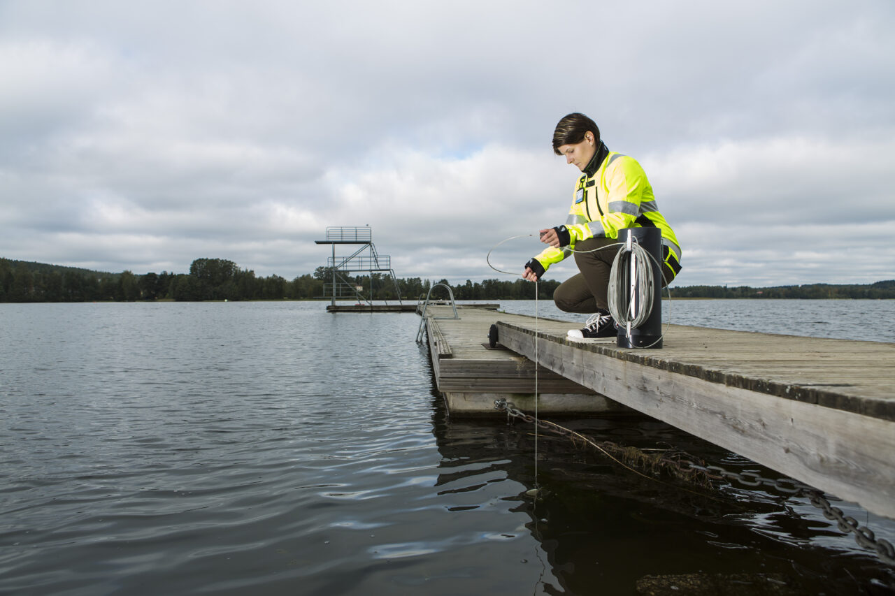 Kuvituskuva, jossa nainen laiturilla ottamassa vesinäytettä