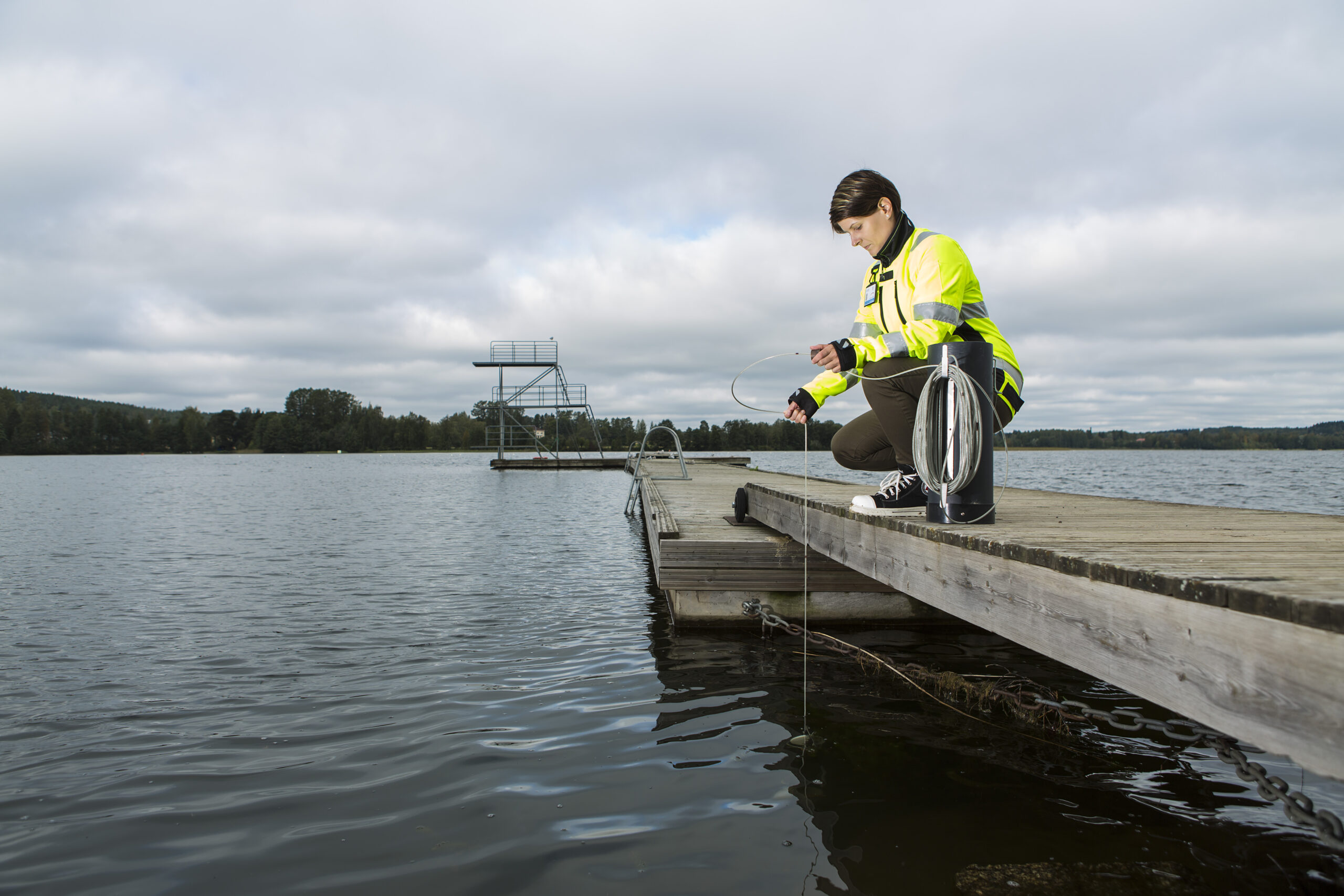 Kuvituskuva, jossa nainen laiturilla ottamassa vesinäytettä