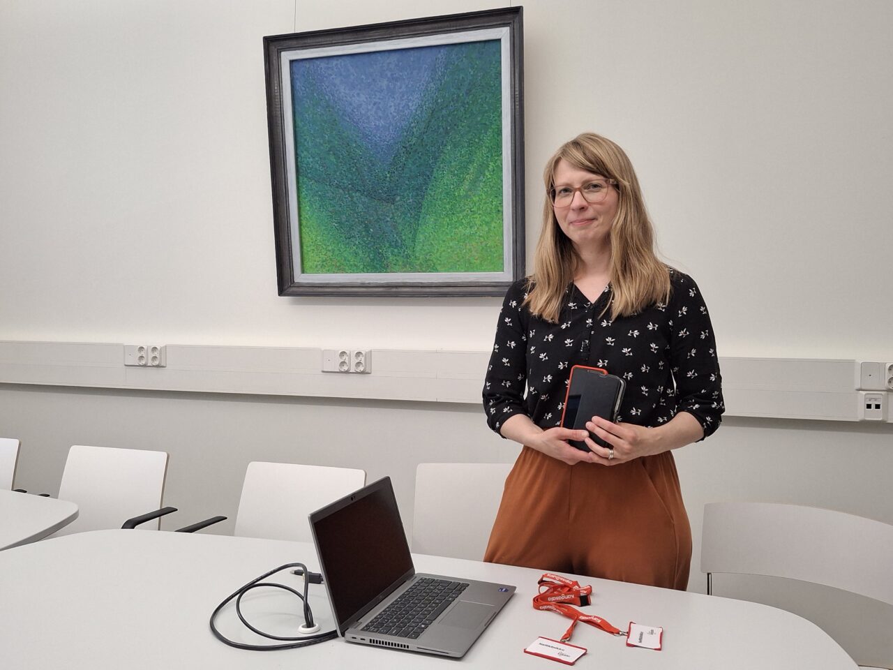 Kirjastonhoitaja, läppäri ja älypuhelimia.