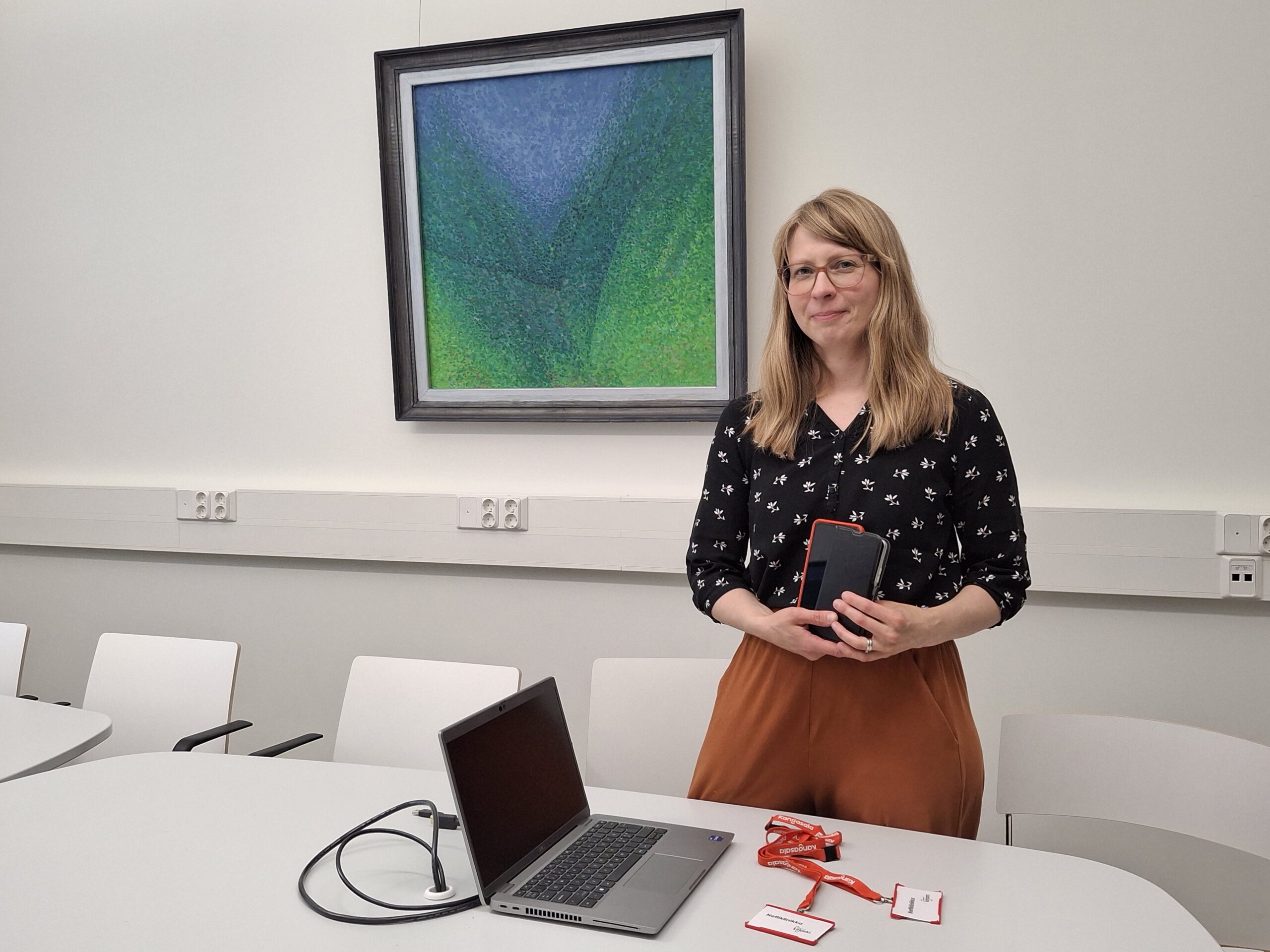 Kirjastonhoitaja, läppäri ja älypuhelimia.