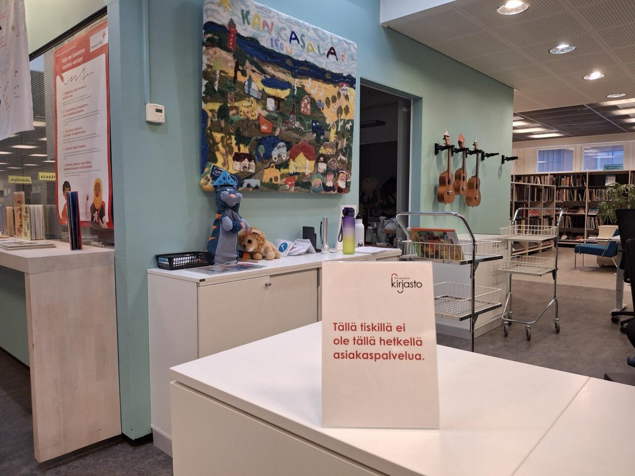 Kirjaston lastenosaston asiakaspalvelutiski, jolla on lappu: Tällä tiskillä ei tällä hetkellä ole asiakaspalvelua.