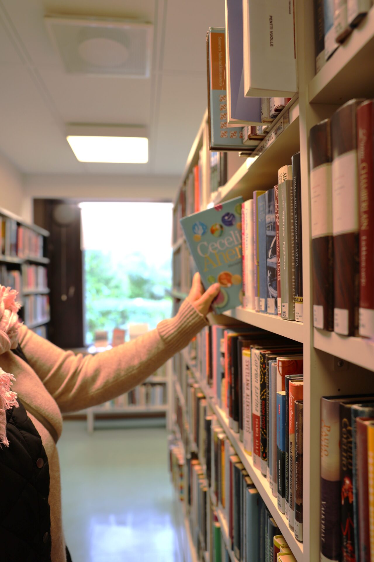 Nainen ottaa kirjan hyllystä.