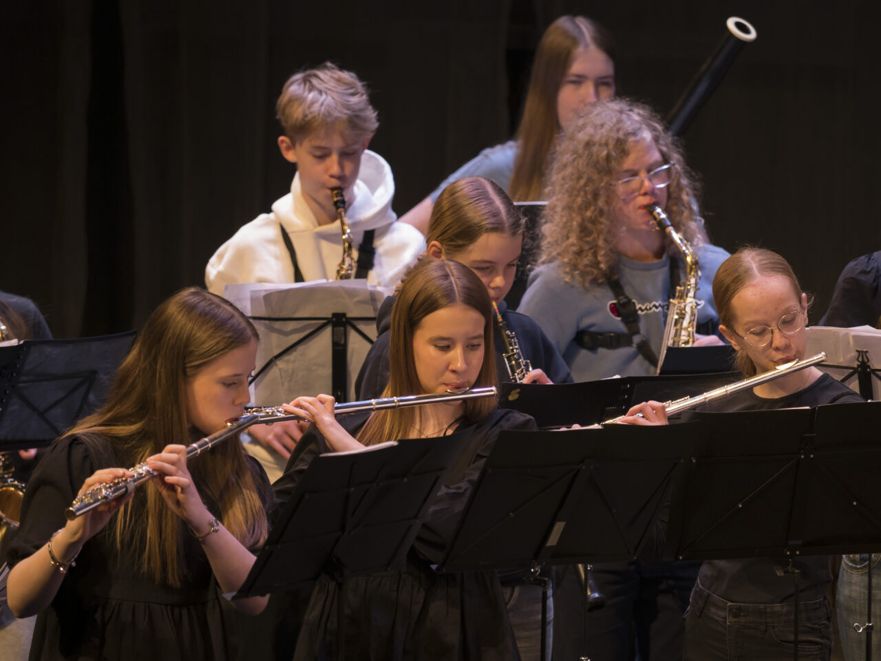 Nuoria soittajia, jotka soittavat orkesterissa puhallinsoittimia