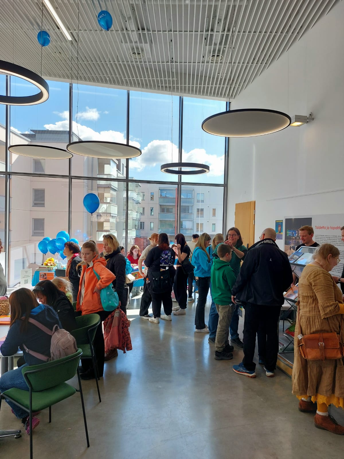 Ihmisiä tutustumassa näytteilleasettajien pöytiin.