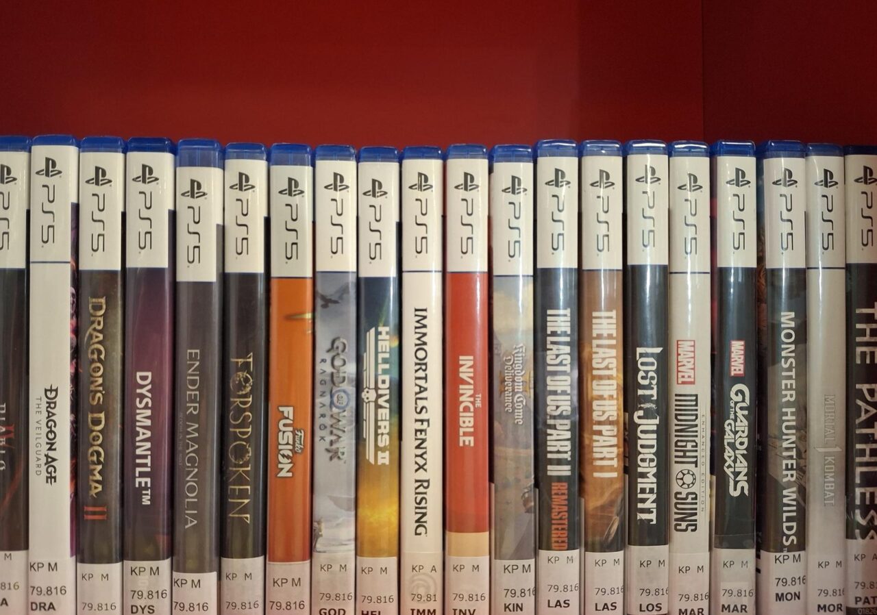 Play Station 5 -konsolin pelejä rivissä punataustaisessa hyllyssä.