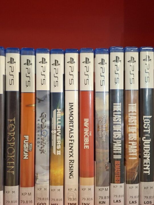 Play Station 5 -konsolin pelejä rivissä punataustaisessa hyllyssä.