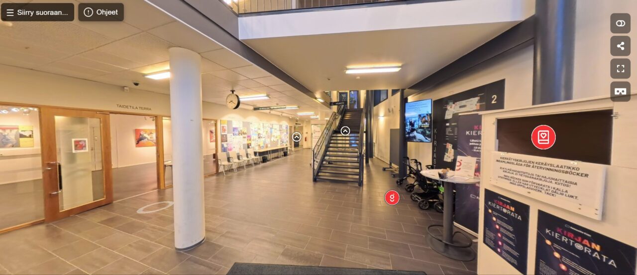 Kirjaston ala-aulaa virtuaalikierrokselta. Tilassa näkyy valkoisia ja punaisia painikkeita tilassa liikkumista ja lisätietojen hankkimista varten.